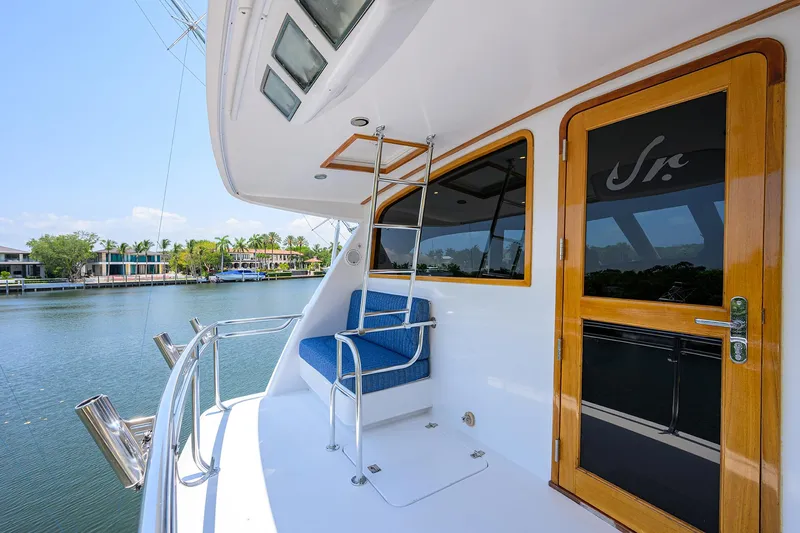 Slide: The Image of 2004 Sea Force IX 82 Enclosed Bridge yacht deck with seating and ladder, docked by waterfront homes. - 4
