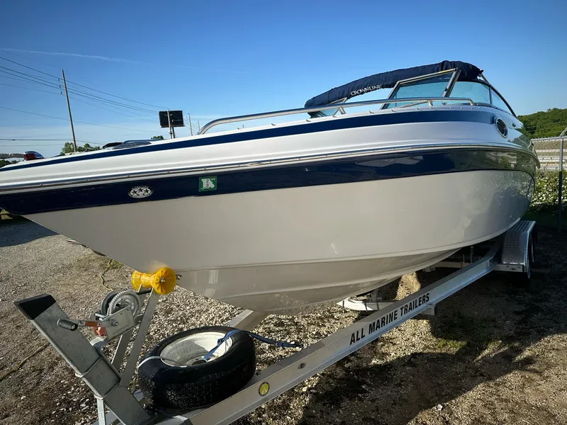 Slide: The Image of 2006 Crownline 270 BR boat on trailer, white and blue, parked outdoors. - 14