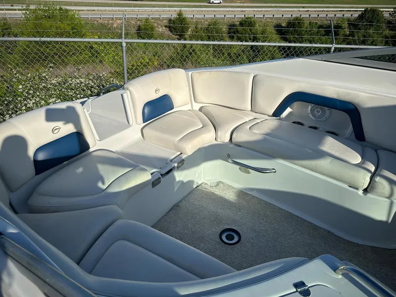 Slide: The Image of 2006 Crownline 270 BR boat interior with white and blue seating, near highway and fence. - 9