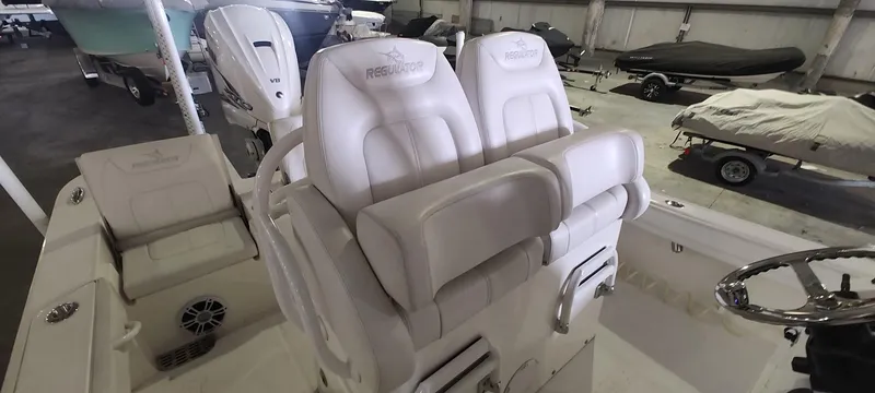Slide: The Image of 2023 Regulator 26XO boat interior with dual white seats in a showroom. - 15