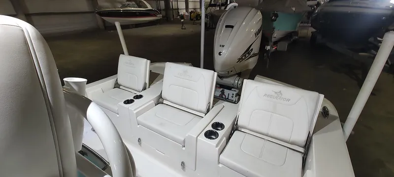 Slide: The Image of 2023 Regulator 26XO boat interior with seating and outboard motor in a showroom. - 31