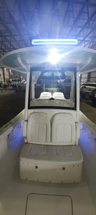 Slide: The Image of 2023 Regulator 26XO boat interior with seating and overhead lighting in a warehouse setting. - 33