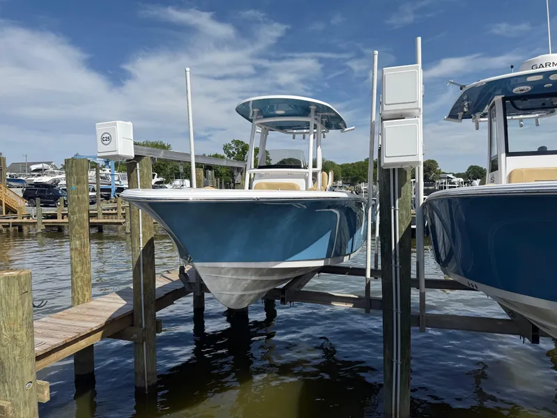 Slide: The Image of 2023 Sportsman Open 232 Center Console boat docked at marina under clear sky. - 1