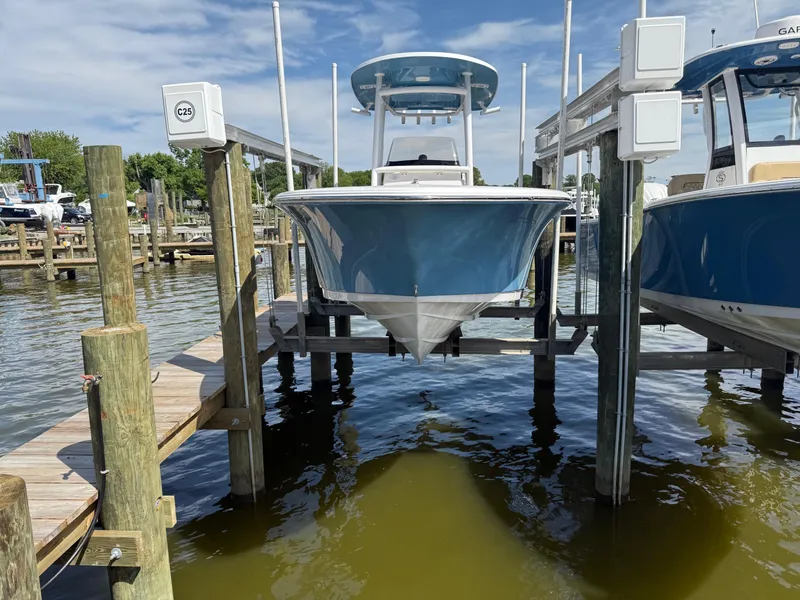 Slide: The Image of 2023 Sportsman Open 232 Center Console boat on a lift at a marina. - 2