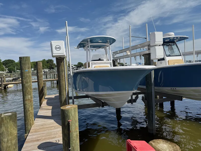Slide: The Image of 2023 Sportsman Open 232 Center Console boat docked at marina under clear sky. - 3