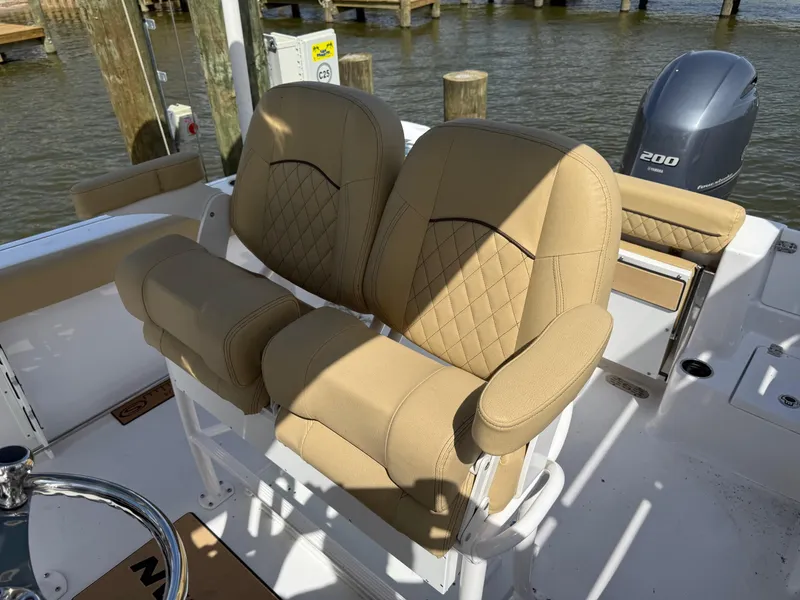 Slide: The Image of 2023 Sportsman Open 232 Center Console boat with tan cushioned seats and steering wheel. - 9