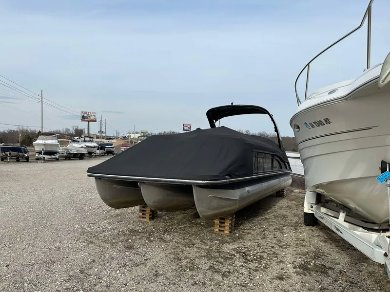 Slide: The Image of 2016 Bennington 2875 QCW I/O pontoon boat covered and stored on blocks outdoors. - 0