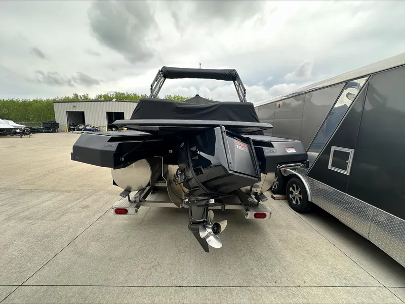 Slide: The Image of 2023 Manitou Explore boat with Rotax engine on trailer, parked outdoors. - 4