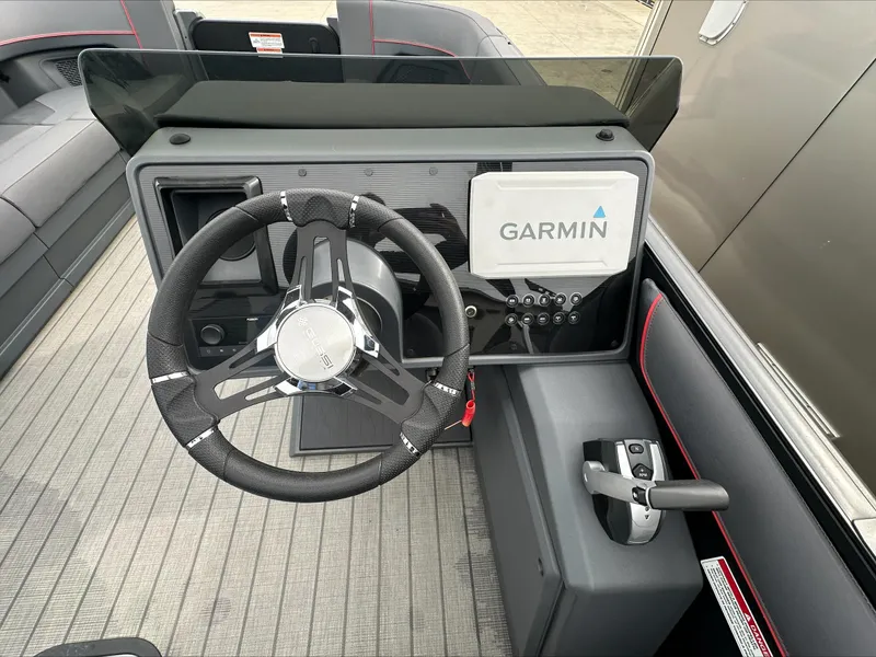 Slide: The Image of 2023 Manitou Explore boat dashboard with Garmin navigation system and steering wheel. - 9