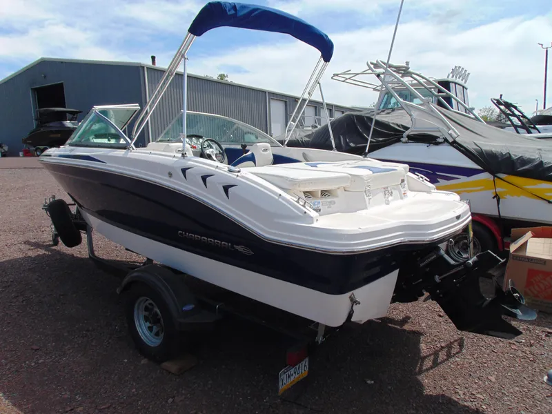 Slide: The Image of 2015 Chaparral 18 H2O Sport boat with blue canopy on trailer, parked outdoors. - 0