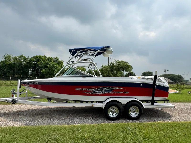 Slide: The Image of 2007 Nautique Super Air Nautique 230 boat on trailer, red and white design, parked outdoors. - 1