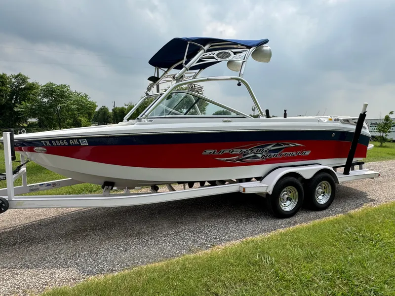 Slide: The Image of 2007 Nautique Super Air Nautique 230 boat on trailer, red and white design, parked outdoors. - 2