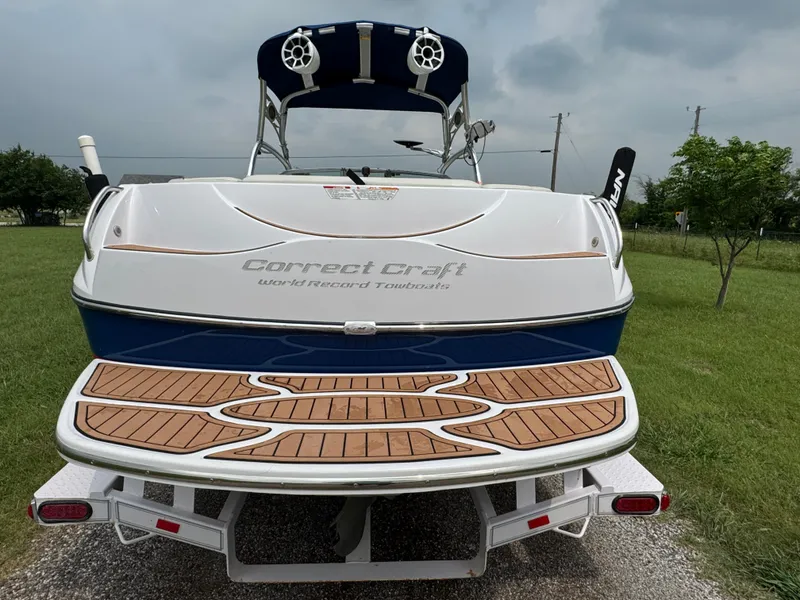 Slide: The Image of 2007 Nautique Super Air Nautique 230 boat with teak swim platform, parked on grass. - 3