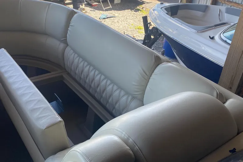 Slide: The Image of 2012 Bennington R22 boat interior with beige seating, parked beside another boat. - 9