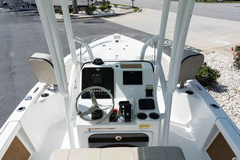 Slide: The Image of 2023 Sea Pro 208 Bay boat console with steering wheel and controls, docked outdoors. - 14