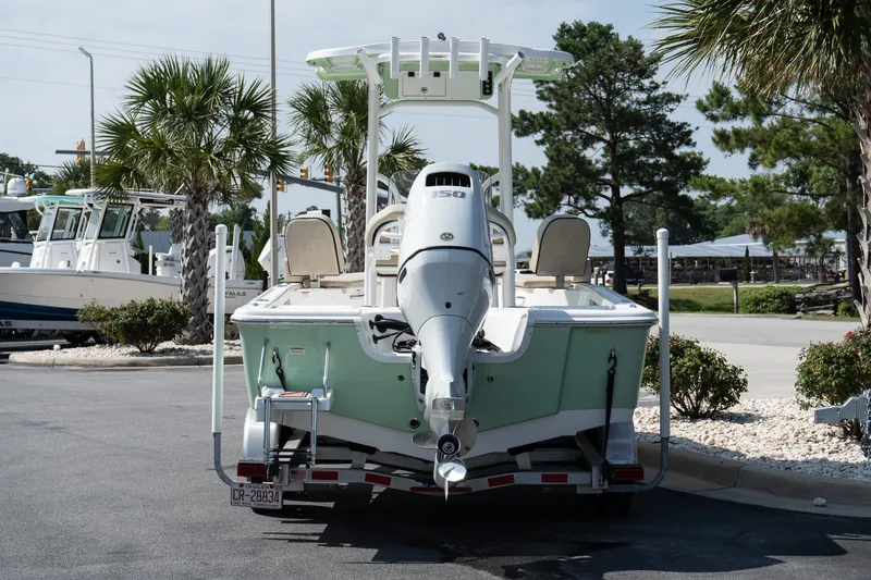 Slide: The Image of 2023 Sea Pro 208 Bay boat on trailer, parked outdoors with palm trees in the background. - 7