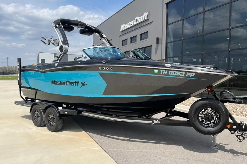 The Image of 2018 MasterCraft XStar boat on trailer, parked outside a modern building. - 1