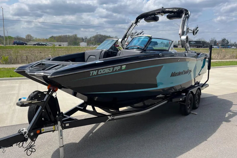 Slide: The Image of 2018 MasterCraft XStar boat on trailer, parked outdoors under cloudy sky. - 4