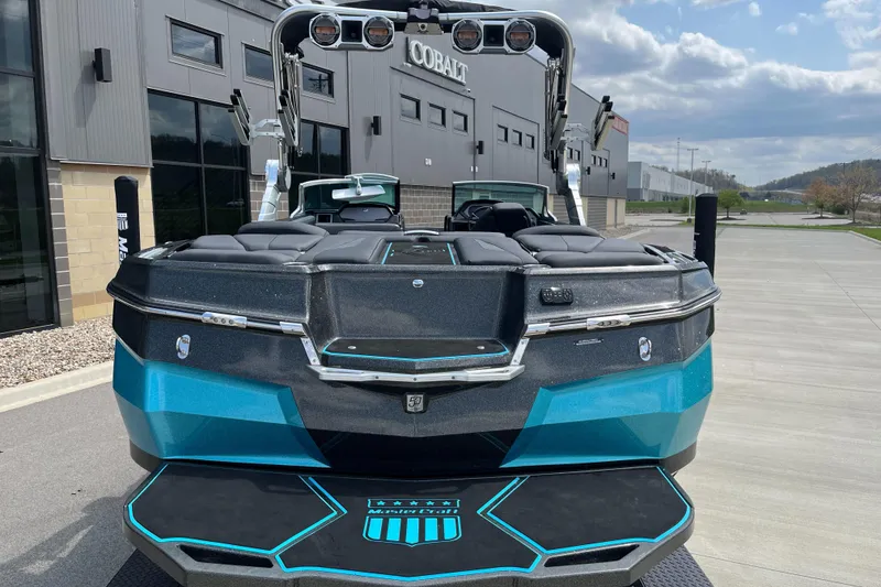 Slide: The Image of 2018 MasterCraft XStar boat with sleek design, parked outdoors near modern buildings. - 8