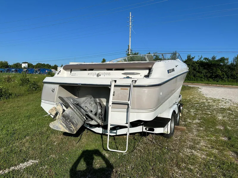Slide: The Image of 1997 Four Winns 240 Horizon boat on trailer, parked on grass under clear blue sky. - 13