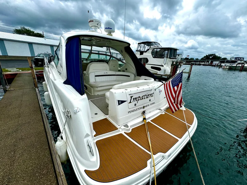 Slide: The Image of 2010 Sea Ray 40 Sundancer docked, featuring American flag and overcast sky. - 8