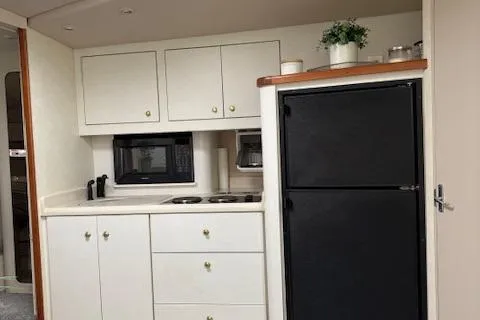 Slide: The Image of 1998 Cruisers 3870 Express yacht kitchen with cabinets, stove, microwave, and refrigerator. - 20