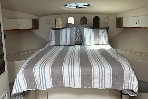 Slide: The Image of 1998 Cruisers 3870 Express cabin with striped bedding and overhead hatch. - 23