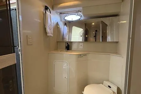 Slide: The Image of 1998 Cruisers 3870 Express yacht bathroom with mirror, sink, and porthole window. - 27