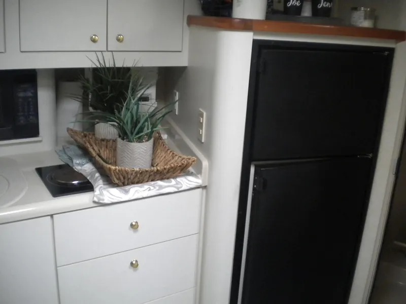 Slide: The Image of 1998 Cruisers 3870 Express yacht kitchen with stove, cabinets, and decorative plants. - 34