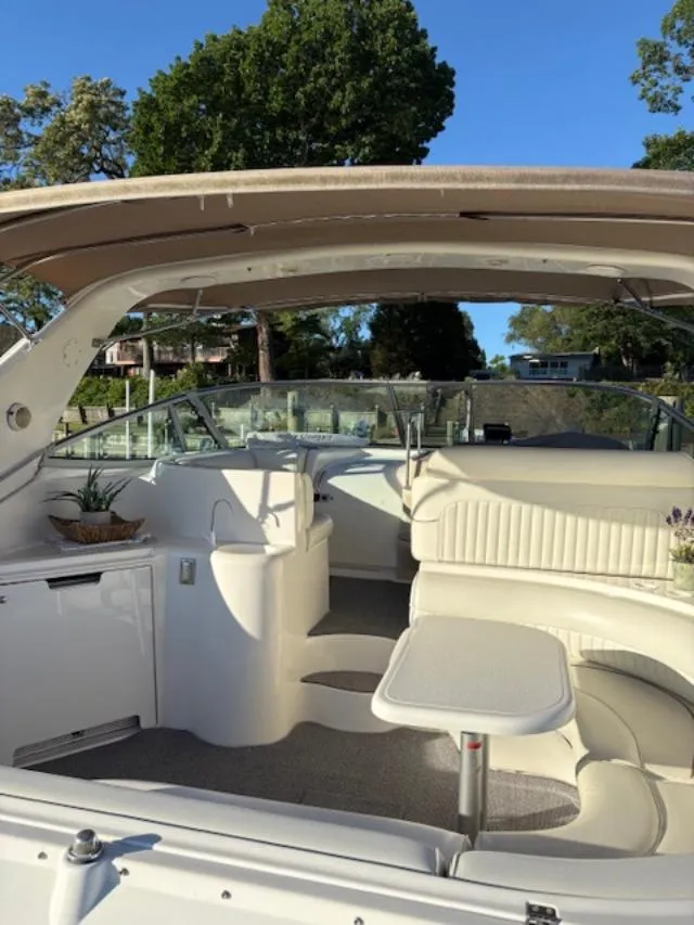 Slide: The Image of 1998 Cruisers 3870 Express yacht interior with seating and table, surrounded by lush greenery. - 7