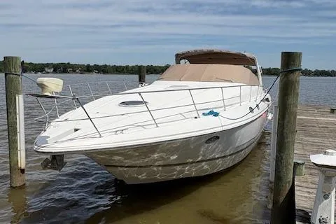 Slide: The Image of 1998 Cruisers 3870 Express yacht docked on calm water under a clear sky. - 2