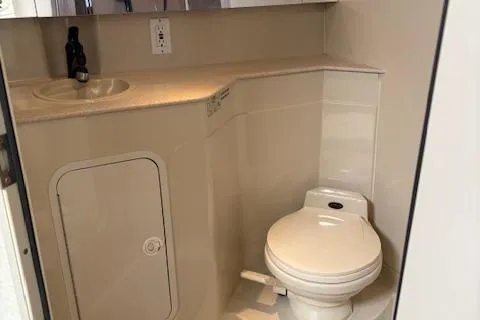 Slide: The Image of 1998 Cruisers 3870 Express boat bathroom with toilet, sink, and storage cabinet. - 26
