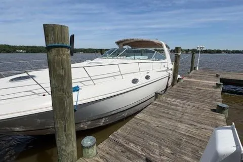 Slide: The Image of 1998 Cruisers 3870 Express yacht docked by a wooden pier on a sunny day. - 3