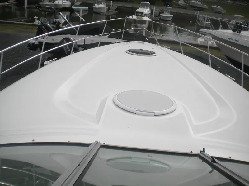 Slide: The Image of 1998 Cruisers 3870 Express yacht bow view at marina, featuring sleek design and hatch. - 30