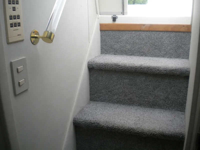 Slide: The Image of Carpeted stairs inside 1998 Cruisers 3870 Express yacht, featuring wall switches and a brass handrail. - 37
