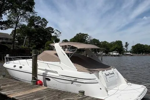Slide: The Image of 1998 Cruisers 3870 Express yacht docked by a serene lakeside with trees in the background. - 4