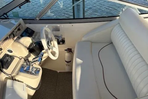 Slide: The Image of 1998 Cruisers 3870 Express helm with white seating and steering wheel, overlooking water. - 8