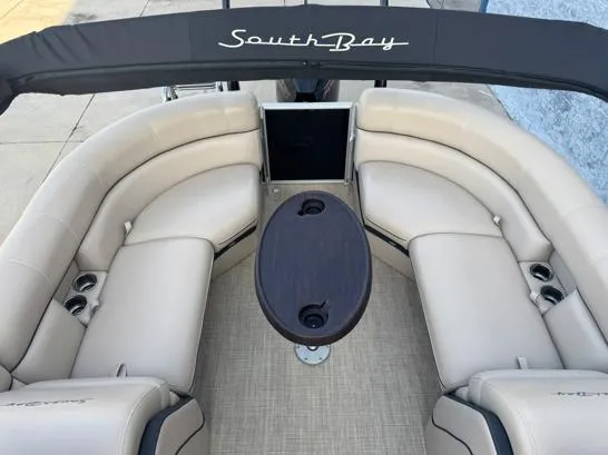 Slide: The Image of 2019 South Bay 521RS 3.0 pontoon boat with beige seating and dark wood table. - 6