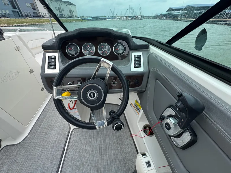 Slide: The Image of 2016 Chaparral 227 SSX boat dashboard with steering wheel and gauges, docked by the marina. - 10