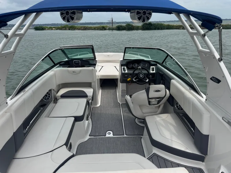 Slide: The Image of 2016 Chaparral 227 SSX boat interior with seating and steering, on a calm lake. - 15