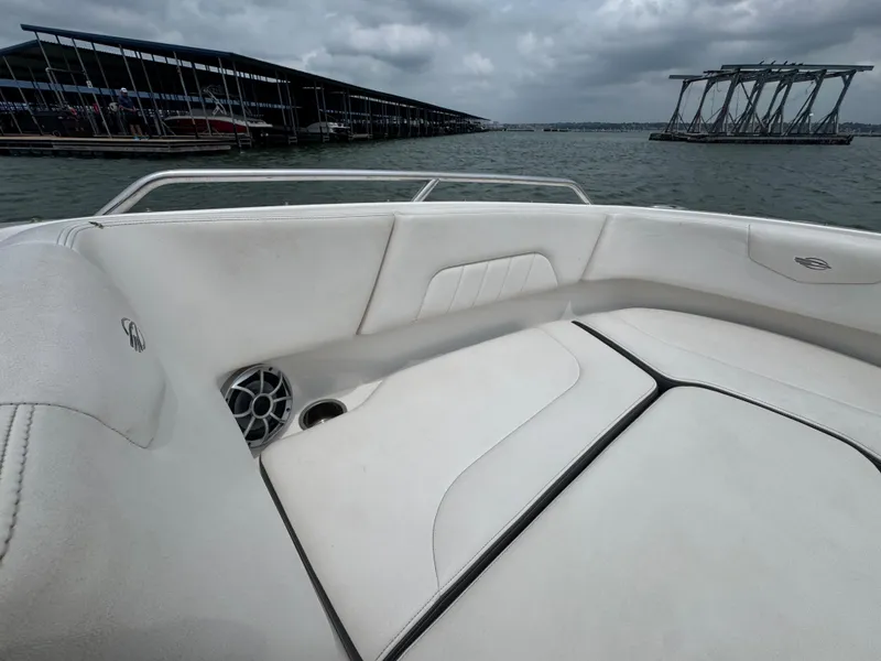 Slide: The Image of 2016 Chaparral 227 SSX boat interior with white seating, docked near marina under cloudy skies. - 6