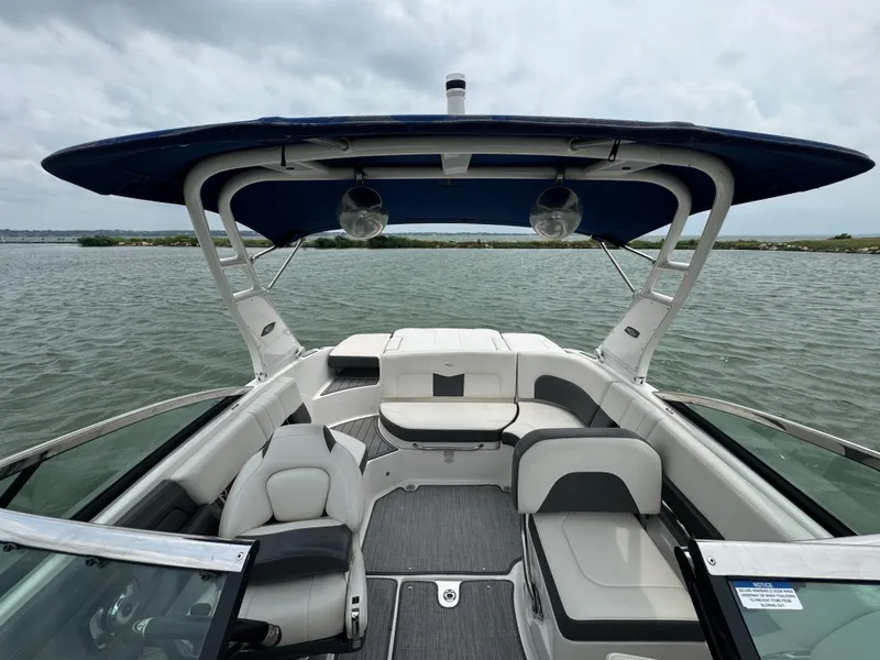 Slide: The Image of 2016 Chaparral 227 SSX boat interior with seating and canopy on a calm lake. - 8