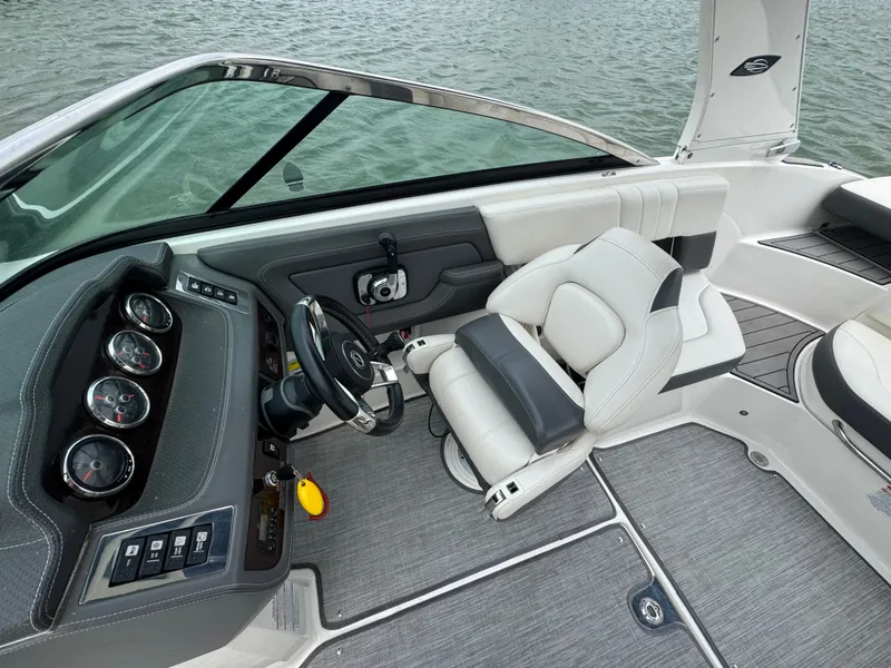 Slide: The Image of 2016 Chaparral 227 SSX boat interior with steering wheel and seating, on calm water. - 9