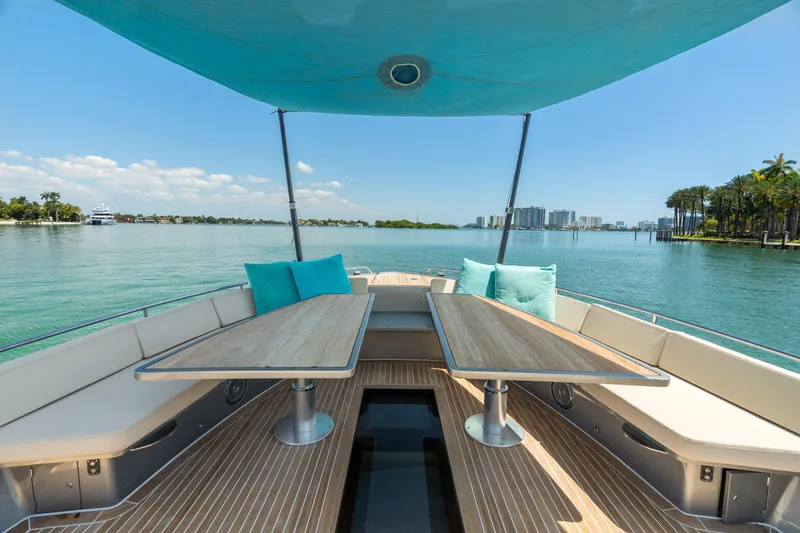 Slide: The Image of Luxurious 2019 CNM Continental 54T yacht deck with tables, overlooking serene waters and cityscape. - 19