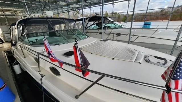 Slide: The Image of 2005 Rinker Fiesta Vee 342 docked, featuring flags and covered seating area. - 2