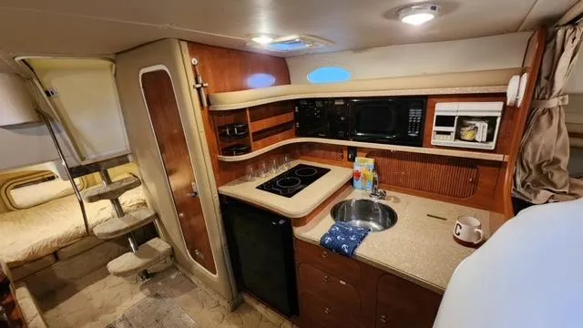 Slide: The Image of 2005 Rinker Fiesta Vee 342 interior with kitchenette, stove, sink, and cozy sleeping area. - 26