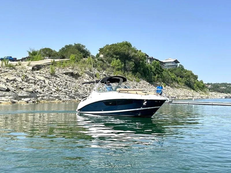 Slide: The Image of 2017 Sea Ray 280 Sundancer boat on a serene lake with rocky shoreline. - 17