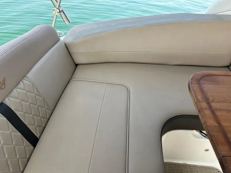 Slide: The Image of 2017 Sea Ray 280 Sundancer interior with beige seating and wooden table, overlooking water. - 27