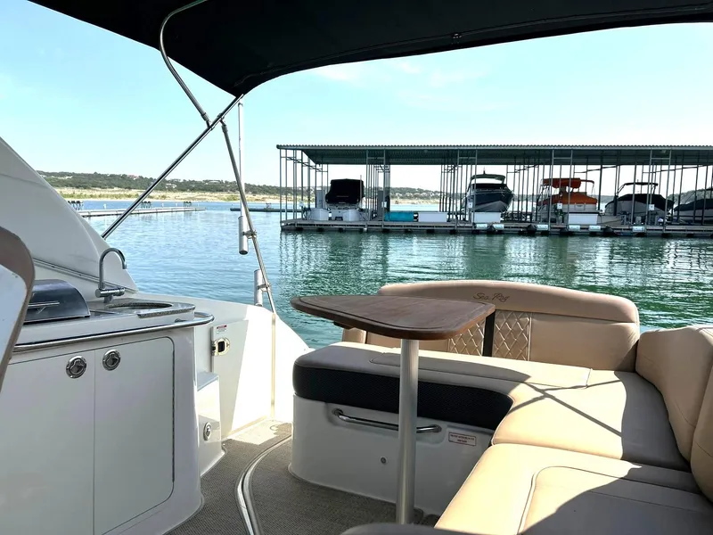 Slide: The Image of 2017 Sea Ray 280 Sundancer interior with seating and table, docked near marina. - 3