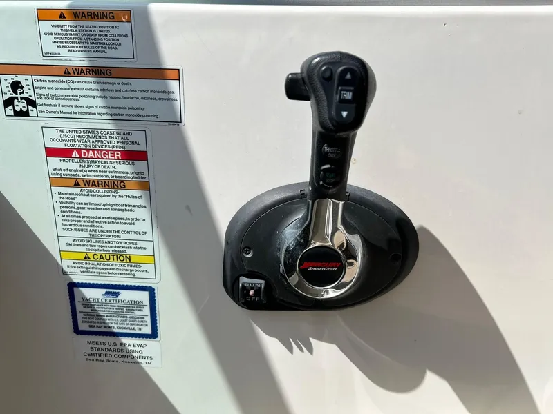 Slide: The Image of Throttle control and warning labels on a 2017 Sea Ray 280 Sundancer boat. - 37